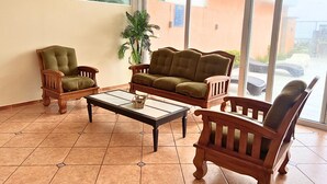 A living room with a glass coffee table, two wooden armchairs, and a sofa. - Quinta del Carmen (La Libertad)