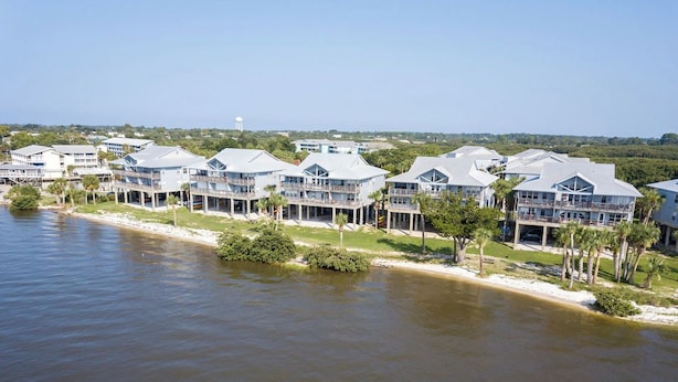 A waterfront property with multiple buildings, each featuring balconies and a view of the water. - Fenimore Mill 4B - Pool, Hot Tub, Open Gulf View! (Cedar Key)