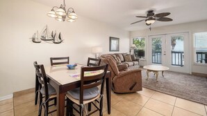 A dining area with a table and chairs, a ceiling fan, and a view of the outdoors through a door. - Fenimore Mill 4B - Pool, Hot Tub, Open Gulf View! (Cedar Key)