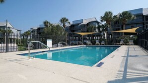 A swimming pool with a metal ladder, surrounded by a fence, and shaded by a yellow canopy. - Fenimore Mill 4B - Pool, Hot Tub, Open Gulf View! (Cedar Key)