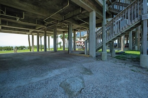 An empty parking area under a concrete structure with visible columns and a staircase. - Fenimore Mill 6A - Open Gulf View, Pool & Hot Tub! (Cedar Key)