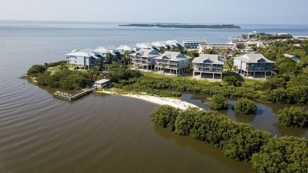 A coastal hotel with multiple buildings, a dock, and lush greenery. - Fenimore Mill 7A - Beautiful View, Pool, Hot Tub! (Cedar Key)