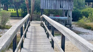 A wooden boardwalk leading to a wooden structure with a roof. - Fenimore Mill 8B - Boat Parking, Pool, Hot Tub! (Cedar Key)