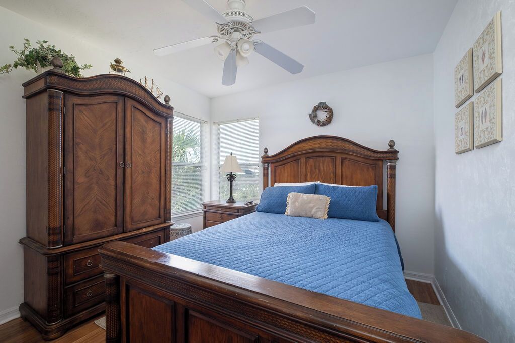Une chambre à coucher avec un grand lit, une armoire en bois et un ventilateur de plafond.