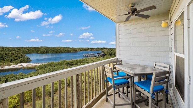 Ein Balkon mit Tisch und Stühlen mit Blick auf einen See und einen Wald.