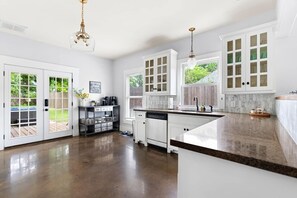 A spacious kitchen with white cabinets, a large island, and a view of the backyard.