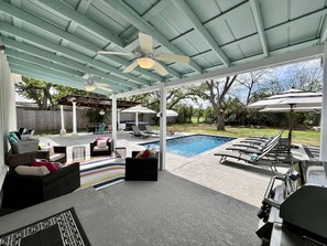A covered patio with a pool, outdoor furniture, and a ceiling fan.