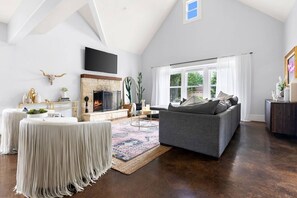 A spacious living room with a fireplace, a gray sofa, and a large window.