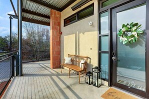 A covered outdoor area with a wooden bench, a small table, and a glass door with a wreath.