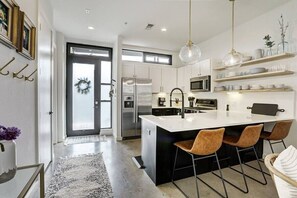 A modern kitchen with a central island, stainless steel appliances, and a black and white color scheme.