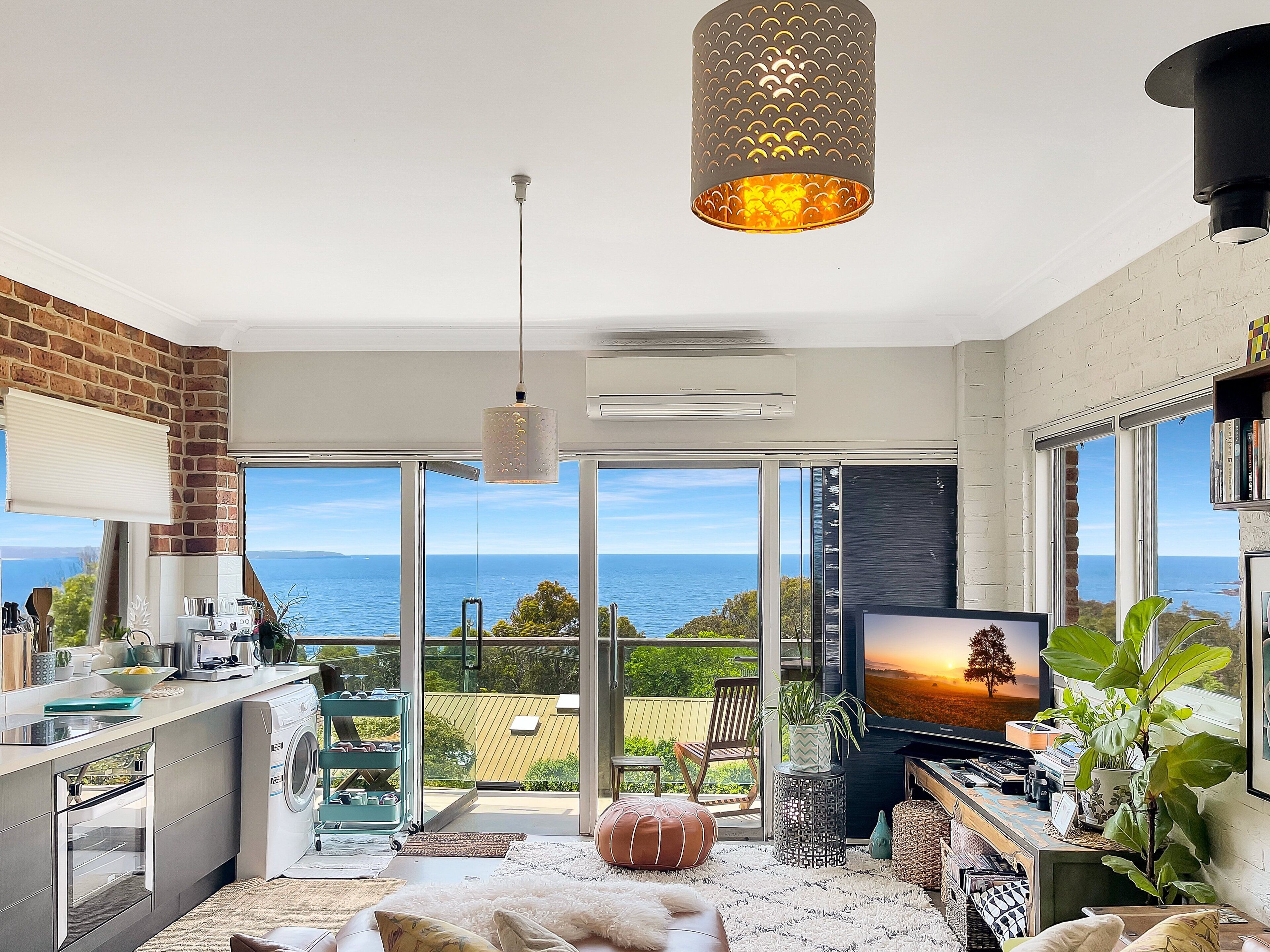 A modern kitchen with a view of the sea, a dining area with a TV, and a cozy seating space with a view.