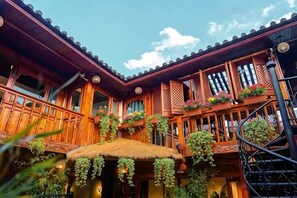 A traditional wooden building with balconies, a thatched roof, and hanging plants.
