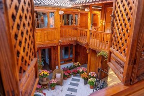 A wooden interior with a balcony, potted plants, and a seating area.
