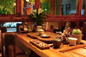 A wooden dining table with various dishes, a vase with flowers, and a potted plant.