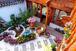 Un patio tradicional con macetas, una silla de madera y un sendero de piedra.