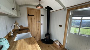 A kitchen with a wooden countertop, a sink, a stove, and a view of the outdoors through a window.
