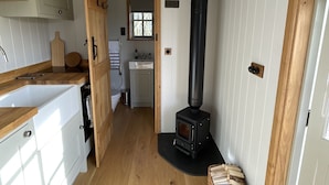 A kitchen with a wood-burning stove, white cabinets, and a wooden floor.