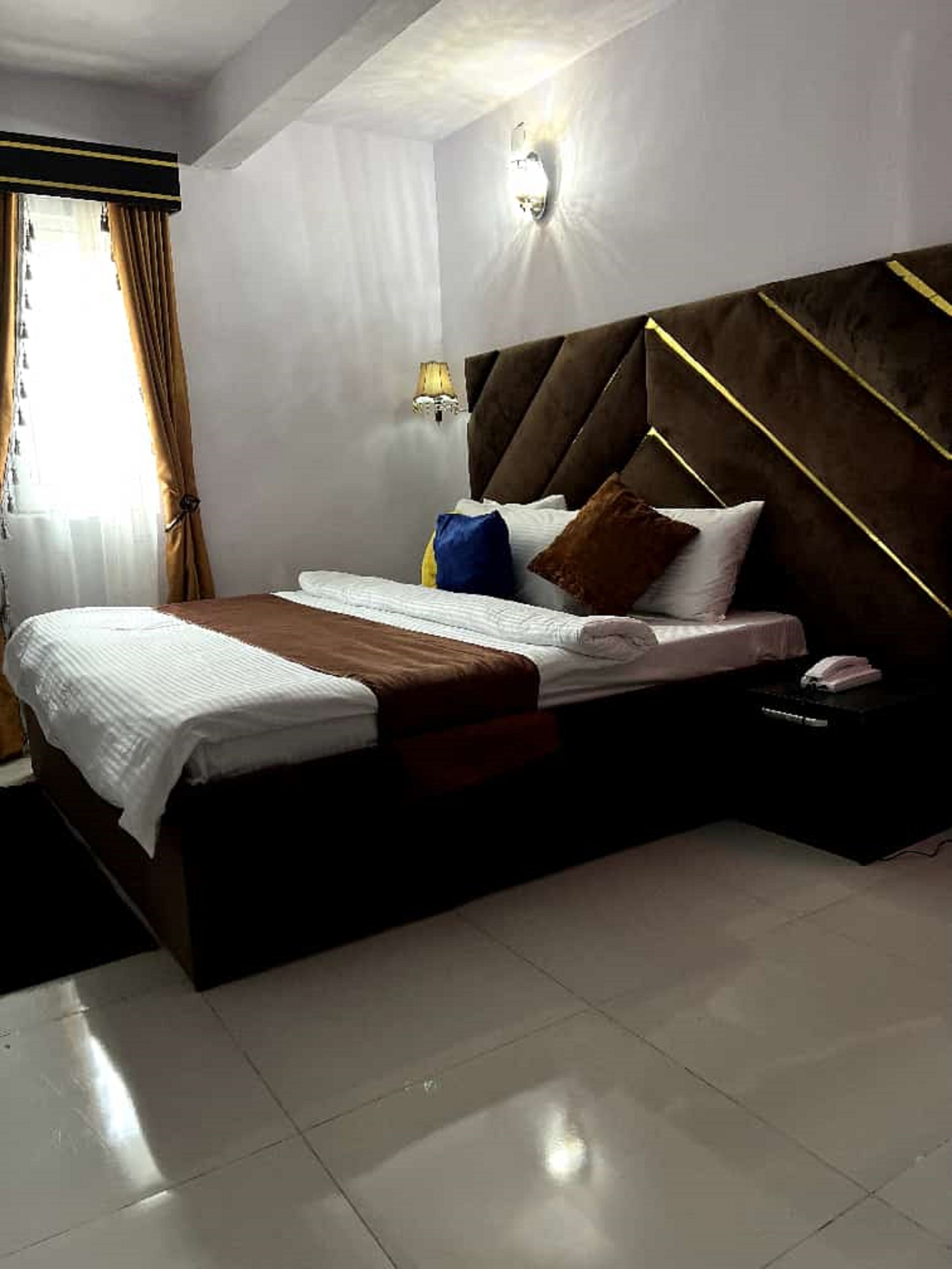 A modern bedroom with a large bed, a bedside table, and a wall-mounted light fixture.