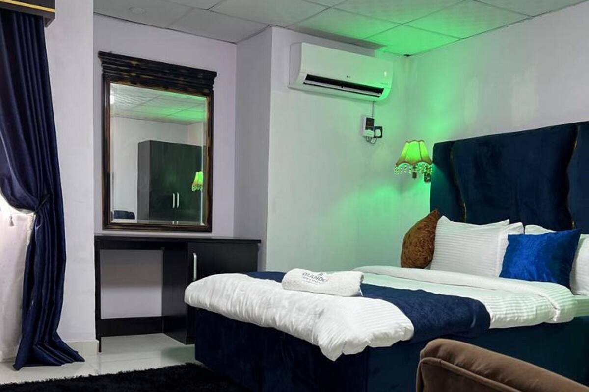 Un dormitorio moderno con cama, escritorio y equipo de aire acondicionado.