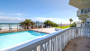 Ein Pool mit Blick auf den Ozean, umgeben von einem weißen Zaun und Palmen.