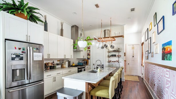 A modern kitchen with stainless steel appliances, a marble island, and a bar area. - Chic Surroundings in Uptown New Orleans! (New Orleans)