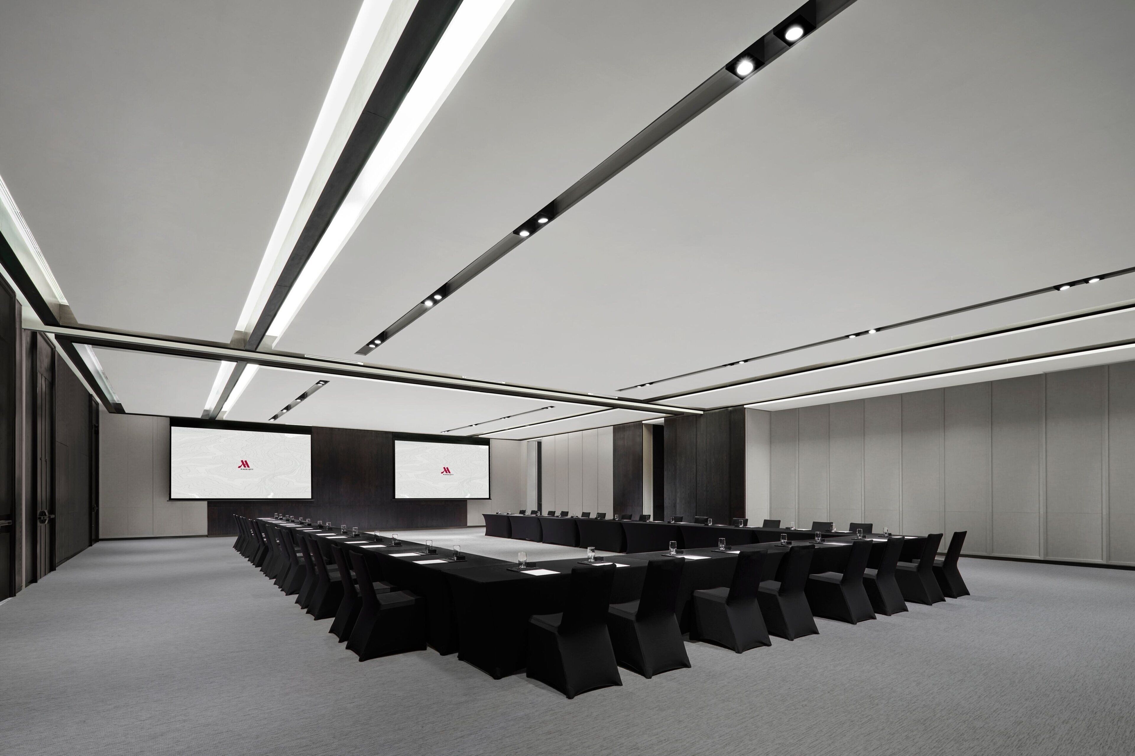 A conference room with a long table, multiple chairs, and a large screen.