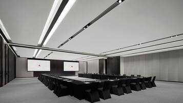 A conference room with a long table, multiple chairs, and a large screen.