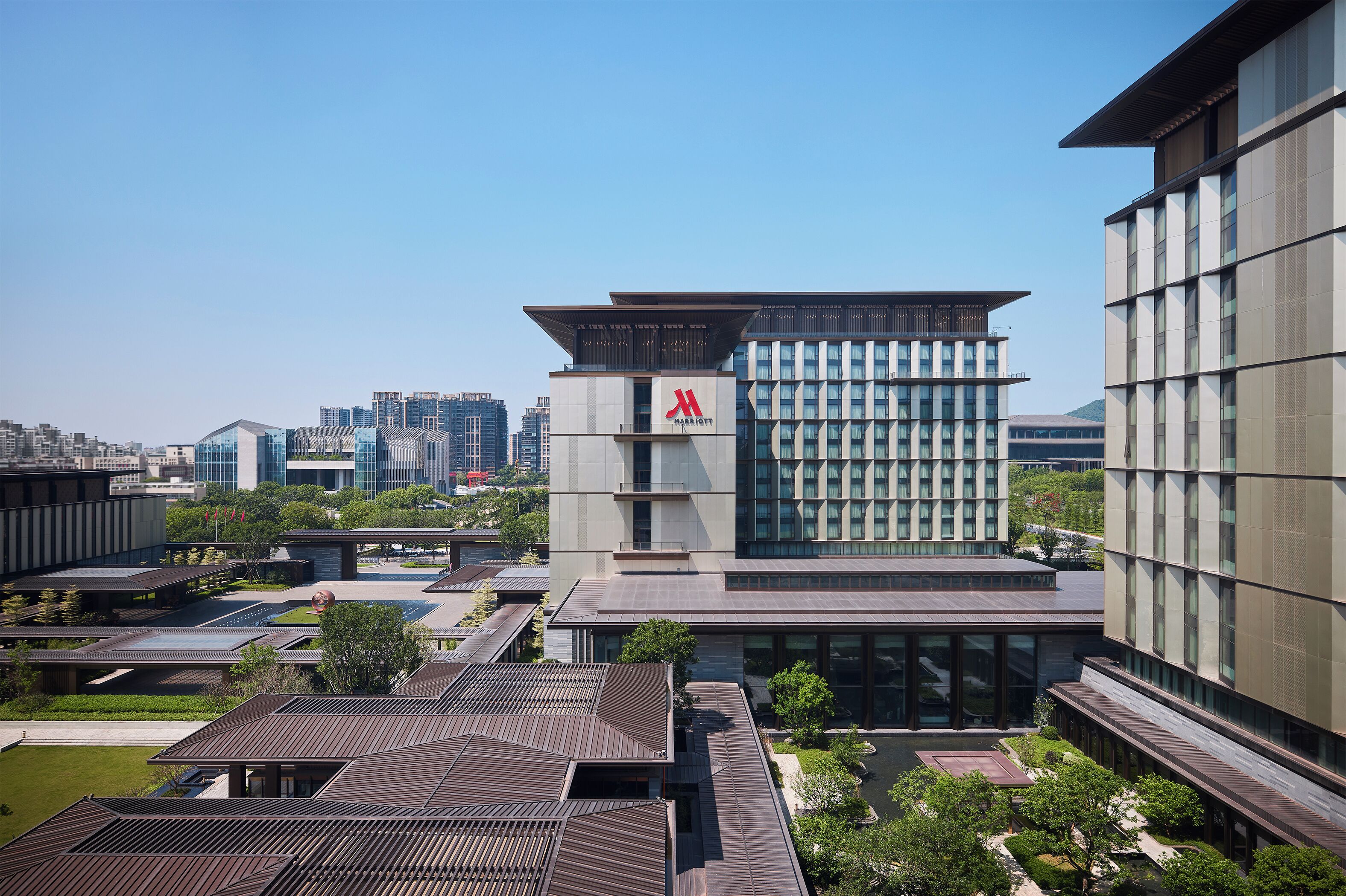 A modern building with a prominent logo, surrounded by other structures and greenery.