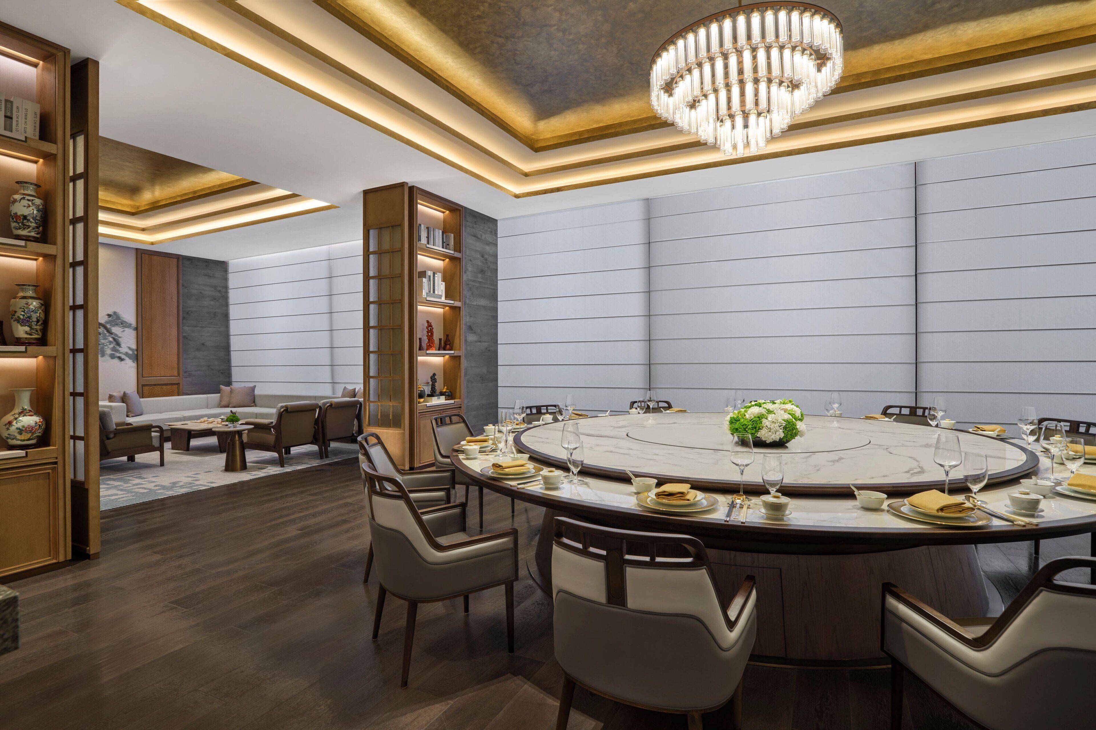 A modern conference room with a round table, chairs, and a chandelier.