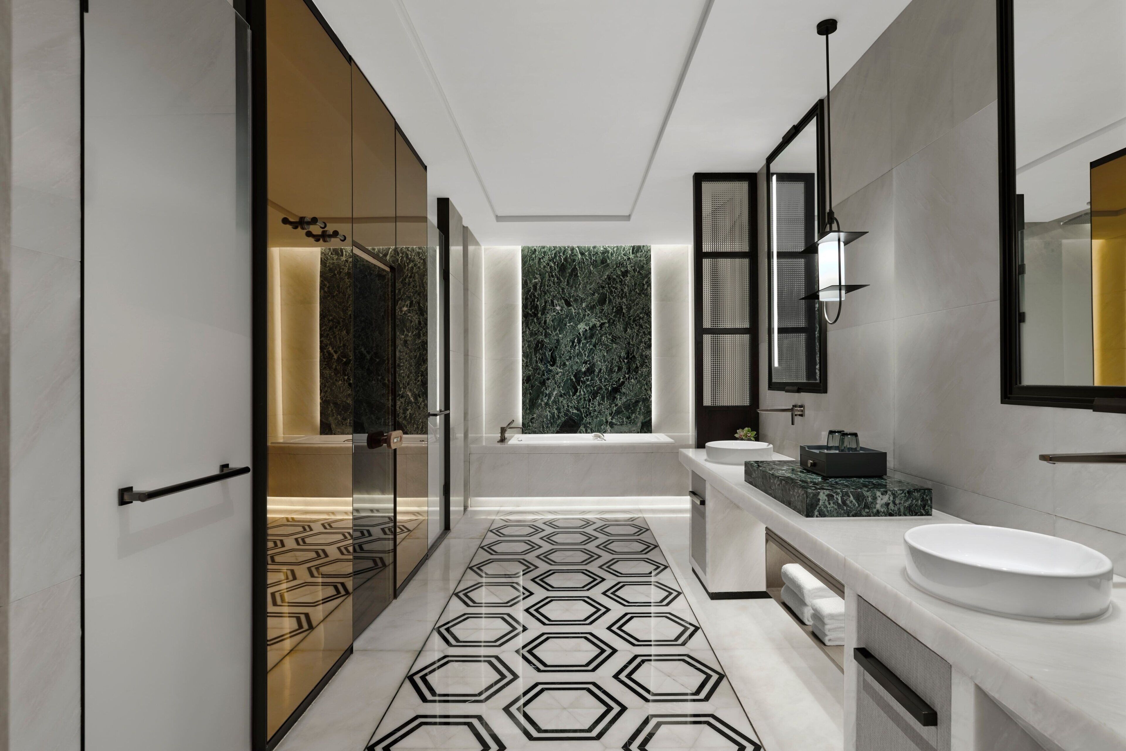 A modern bathroom with a geometric patterned floor, a bathtub, and a large mirror.