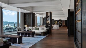 Een moderne hotel lobby met een ruime zithoek, een groot raam met uitzicht op de stad en een goed verlicht interieur.
