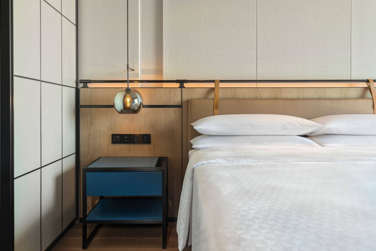 A neatly arranged hotel room with a bed, a nightstand, and a wall-mounted lamp.