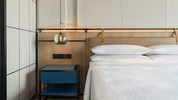 A neatly arranged hotel room with a bed, a nightstand, and a wall-mounted lamp.