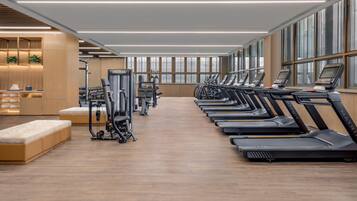 Ein modernes Fitnessstudio mit Laufbändern, Kraftgeräten und Holzboden.