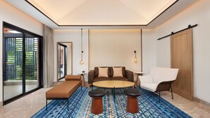 A modern living room with a sofa, coffee table, and chairs, a patterned rug, and a large window with a view of greenery. - Four Points By Sheraton Hainan, Qiongzhong (Qiongzhong County)