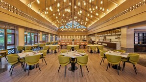A spacious dining area with multiple tables and chairs, a central bar, and a high ceiling with hanging lights. - Four Points By Sheraton Hainan, Qiongzhong (Qiongzhong County)
