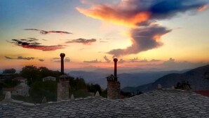 A sunset view with two chimneys and a tiled roof. - Archontiko Polyzos 19 Chrysanthemo (Volos)