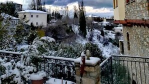 A snowy residential area with stone buildings and a white house in the foreground. - Archontiko Polyzos 19 Chrysanthemo (Volos)