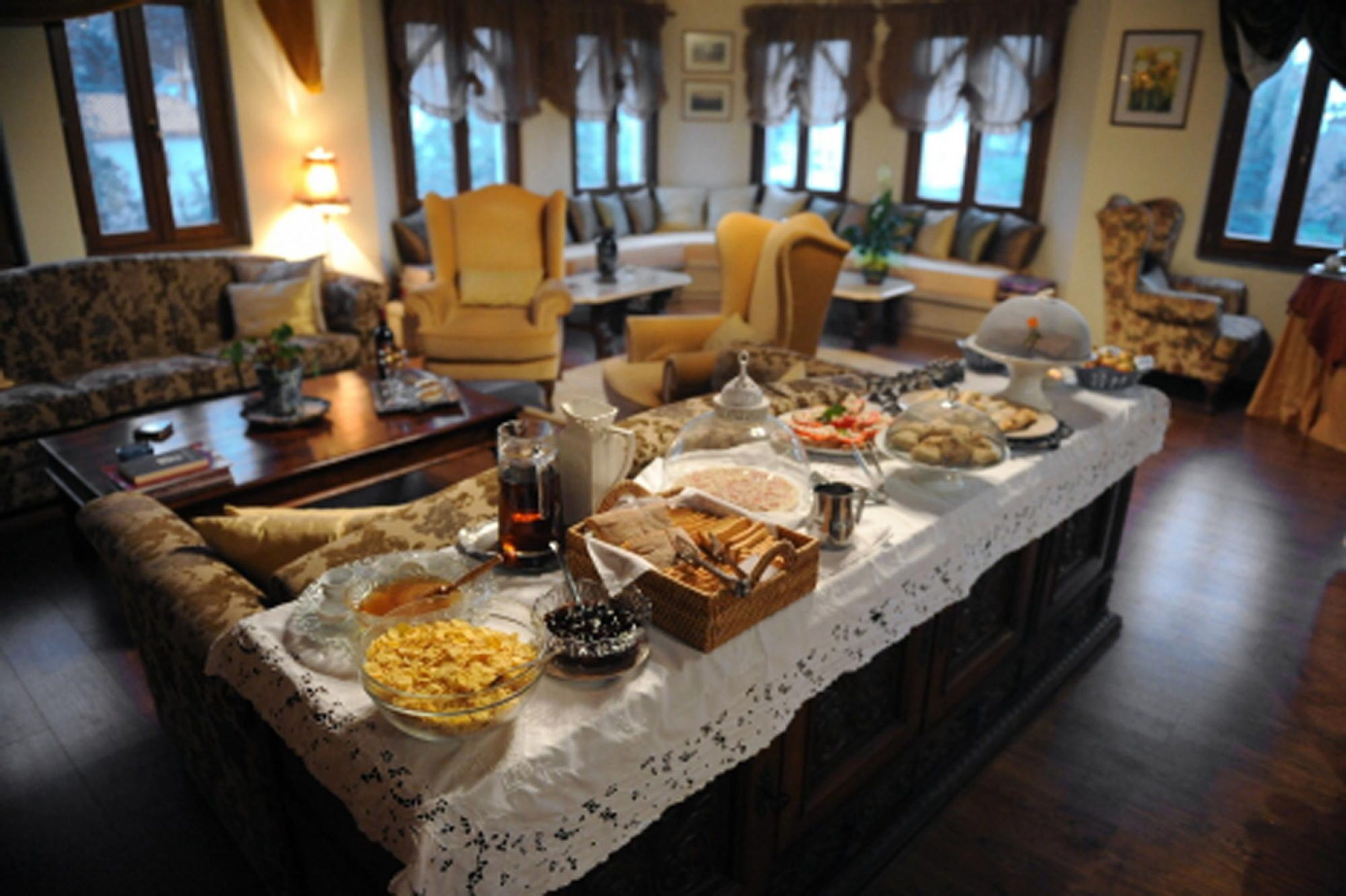 A dining area with a long table set for a meal, surrounded by sofas and chairs.