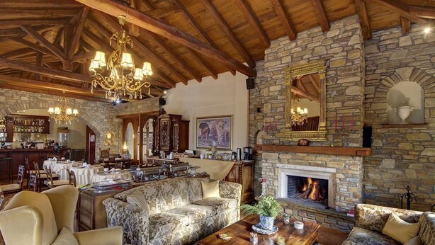 A cozy interior with a stone fireplace, wooden ceiling beams, and a bar area. - Archontiko Polyzos 11 Manolia (Volos)