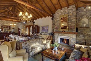 Un intérieur chaleureux avec une cheminée en pierre, des poutres apparentes en bois et un coin bar.