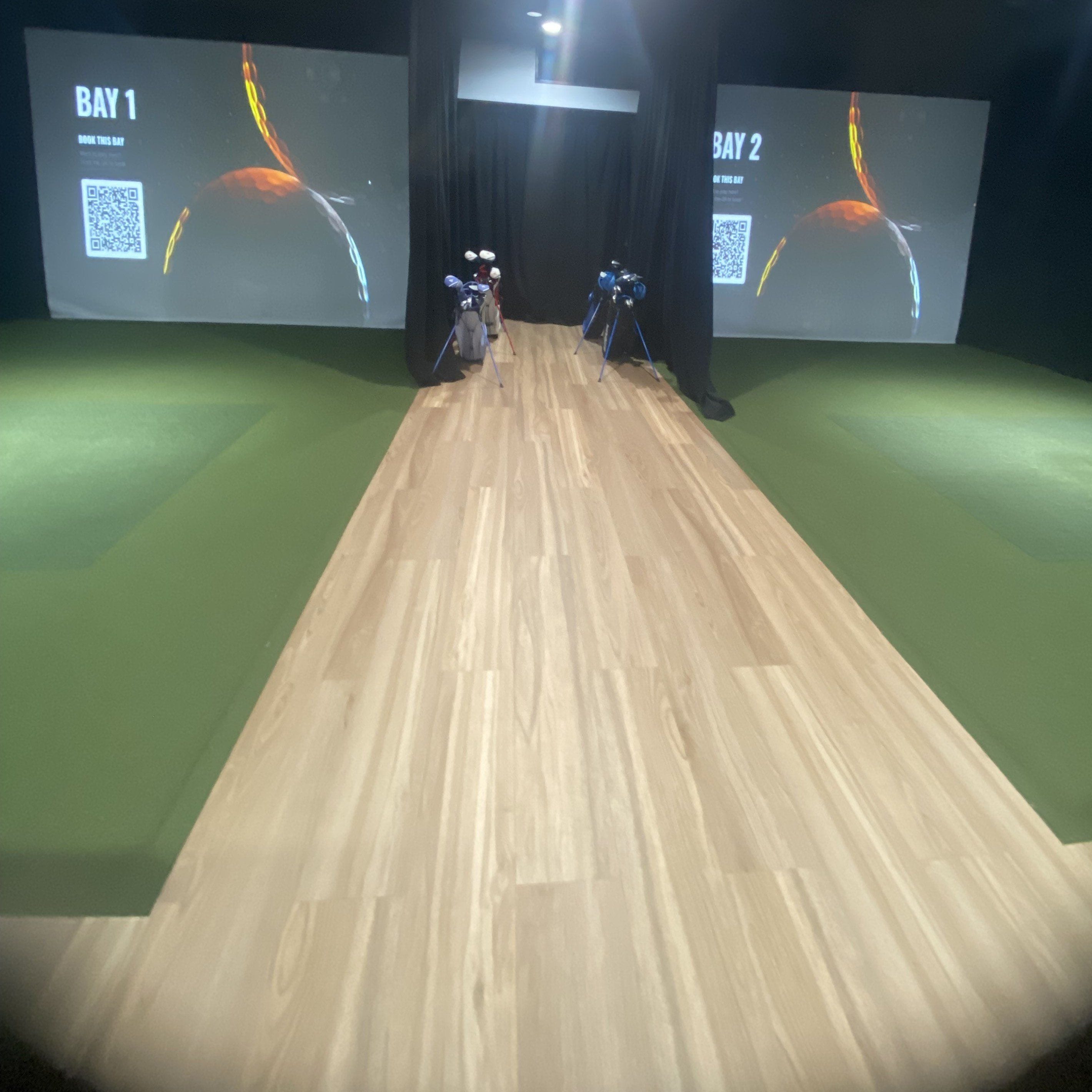 Une salle de bowling avec deux pistes, un plancher en bois et de grands écrans affichant les indications « Piste 1 » et « Piste 2 ».