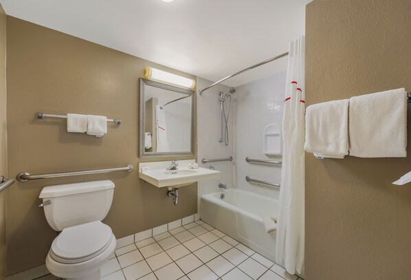 A bathroom with a toilet, sink, shower, and towel rack.