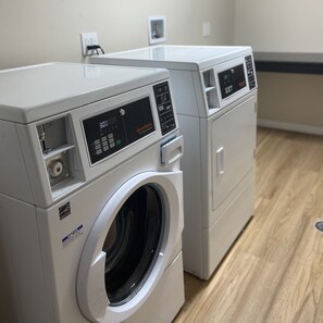 A front-loading washer and dryer in a laundry room with a wooden floor.