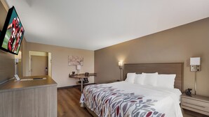A hotel room with a bed, desk, and television.