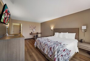 Quarto de hotel com cama, escrivaninha e televisão.