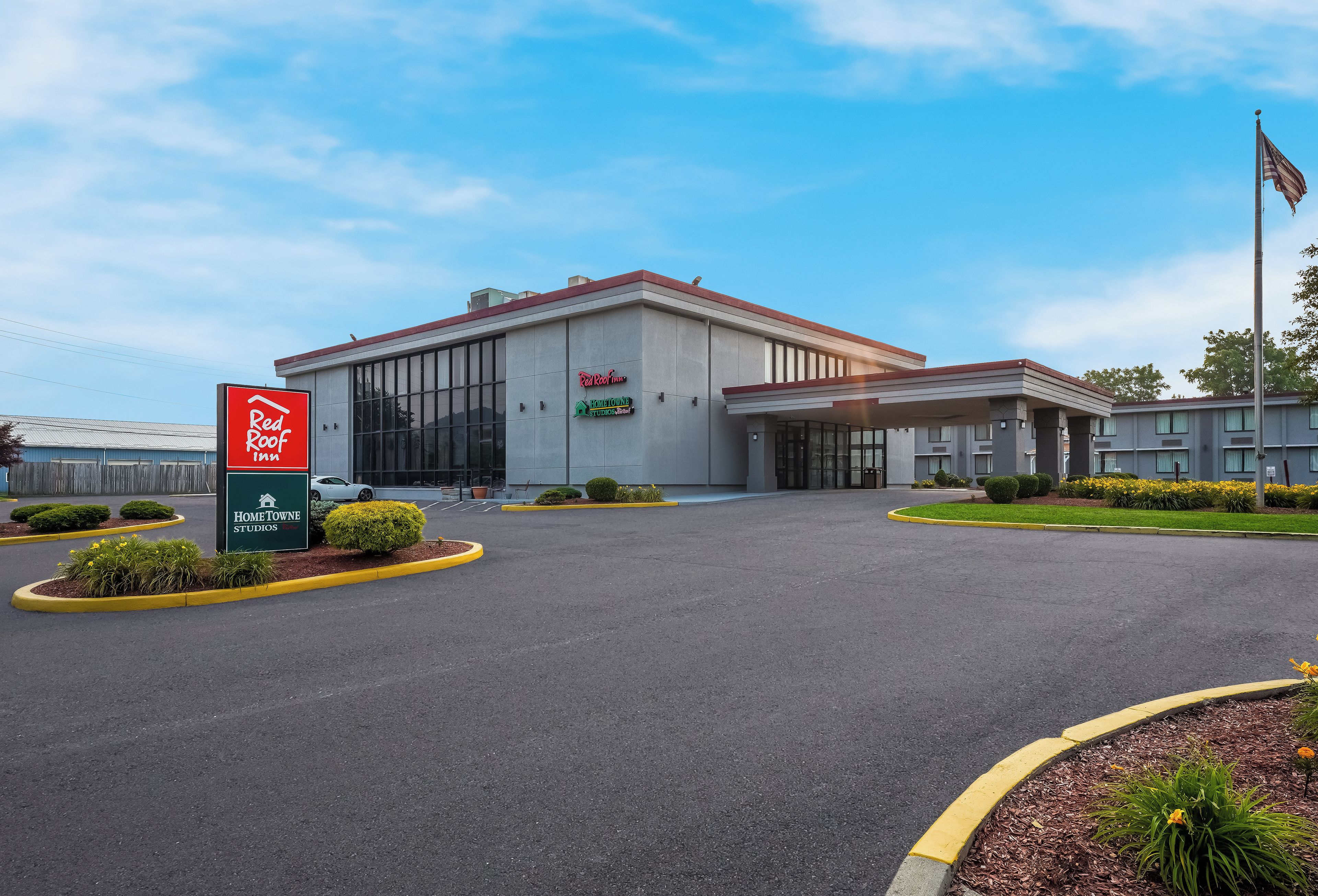 Ein Red Roof Inn mit großem Parkplatz und gepflegtem Rasen.