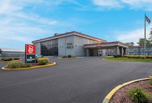 Um Red Roof Inn com um amplo estacionamento e um gramado bem cuidado.