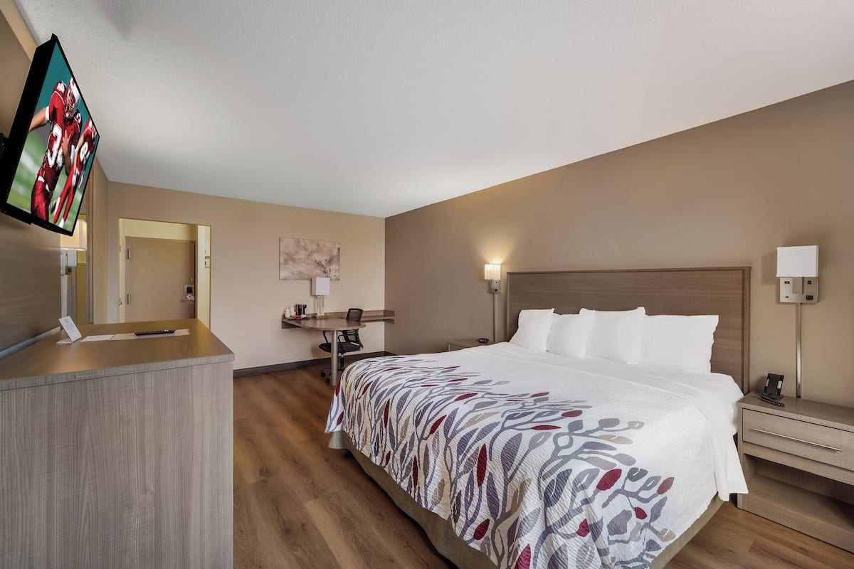 A hotel room with a bed, desk, and TV.