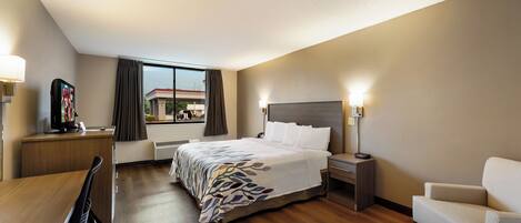 Una habitación de hotel con cama, mesitas de noche, escritorio, silla y televisor.